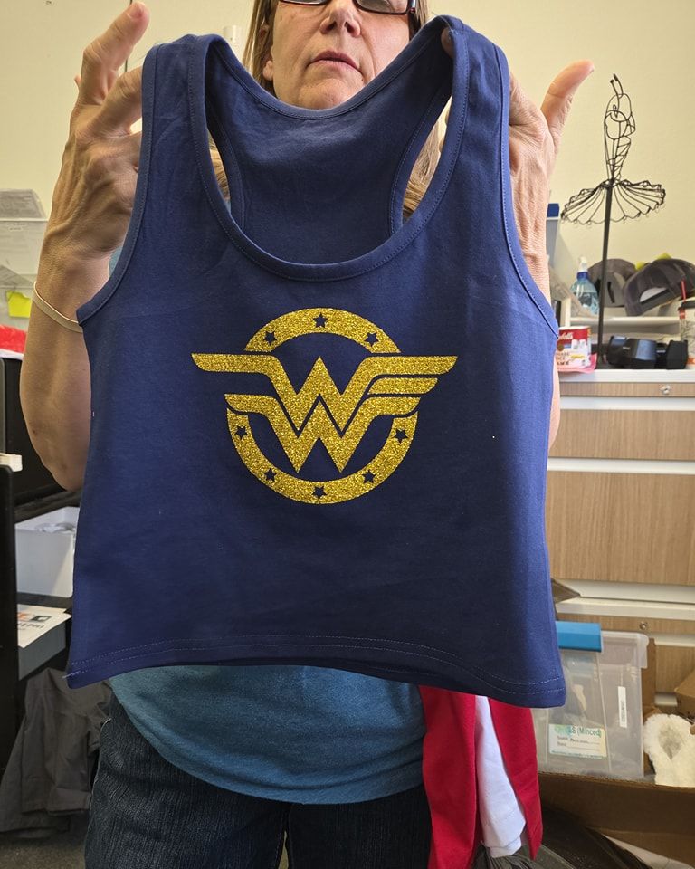 A woman is holding a blue tank top with a wonder woman logo on it
