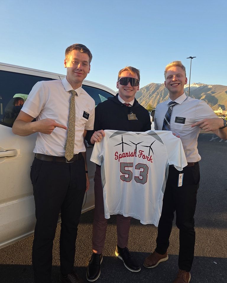 Three men are standing next to each other holding a jersey with the number 53 on it
