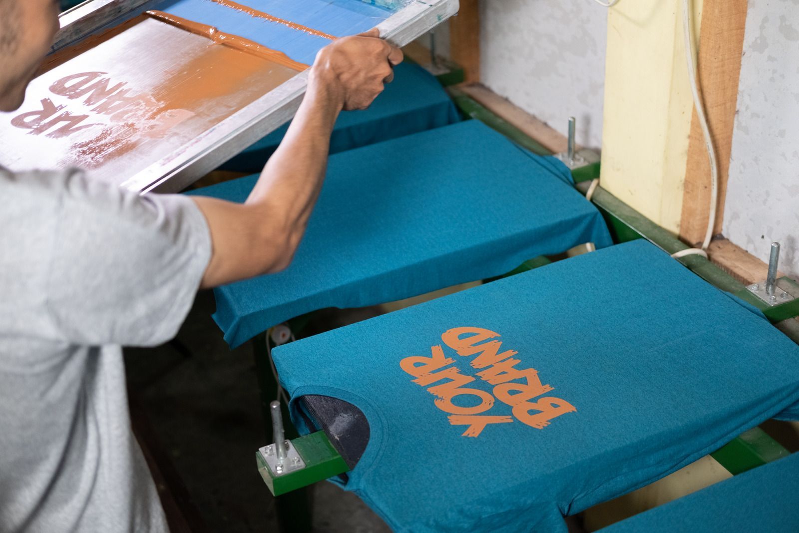 A man is printing t-shirts in a factory.