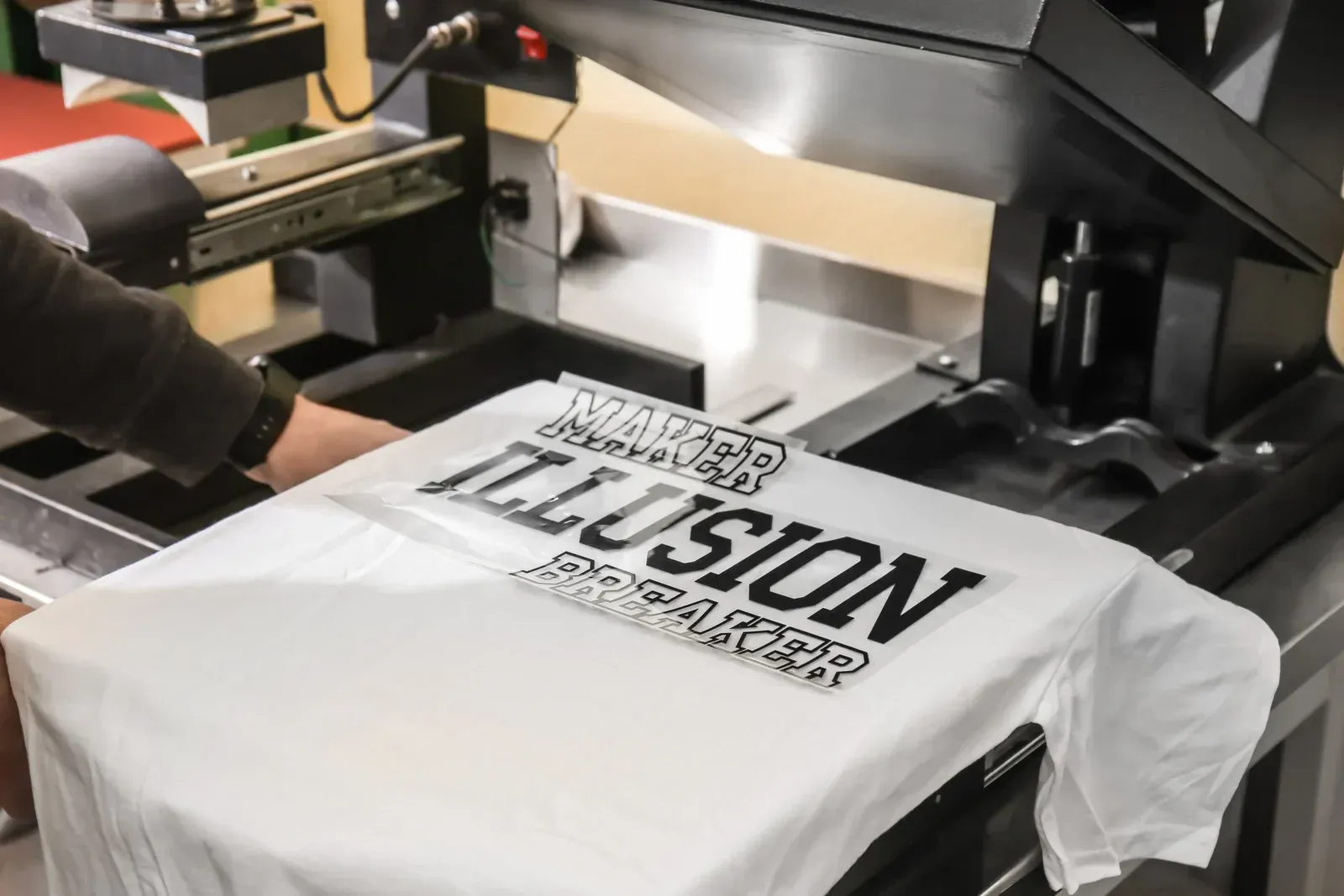 A person is printing a t-shirt on a machine.