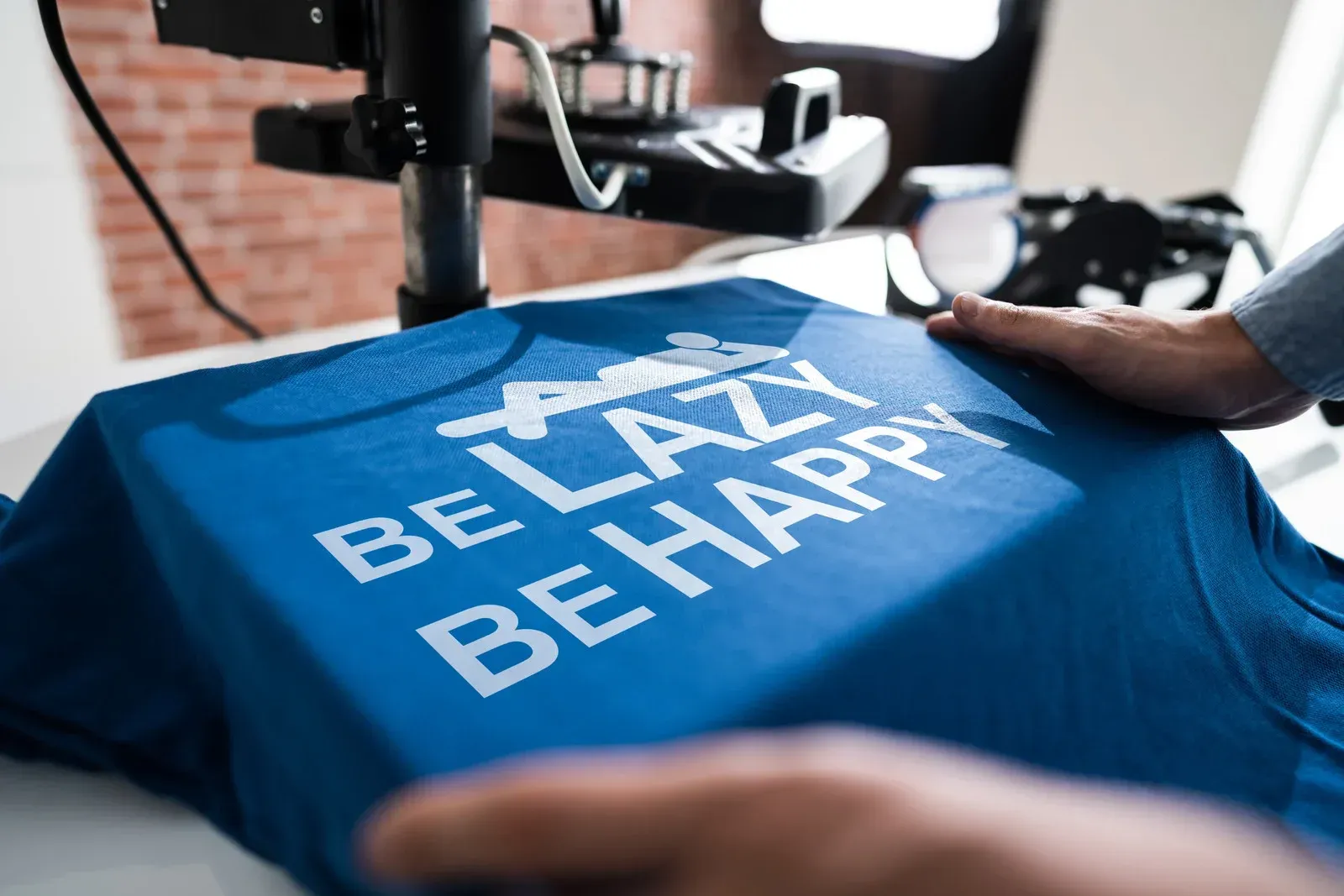 A person is holding a blue shirt that says `` be lazy be happy ''.