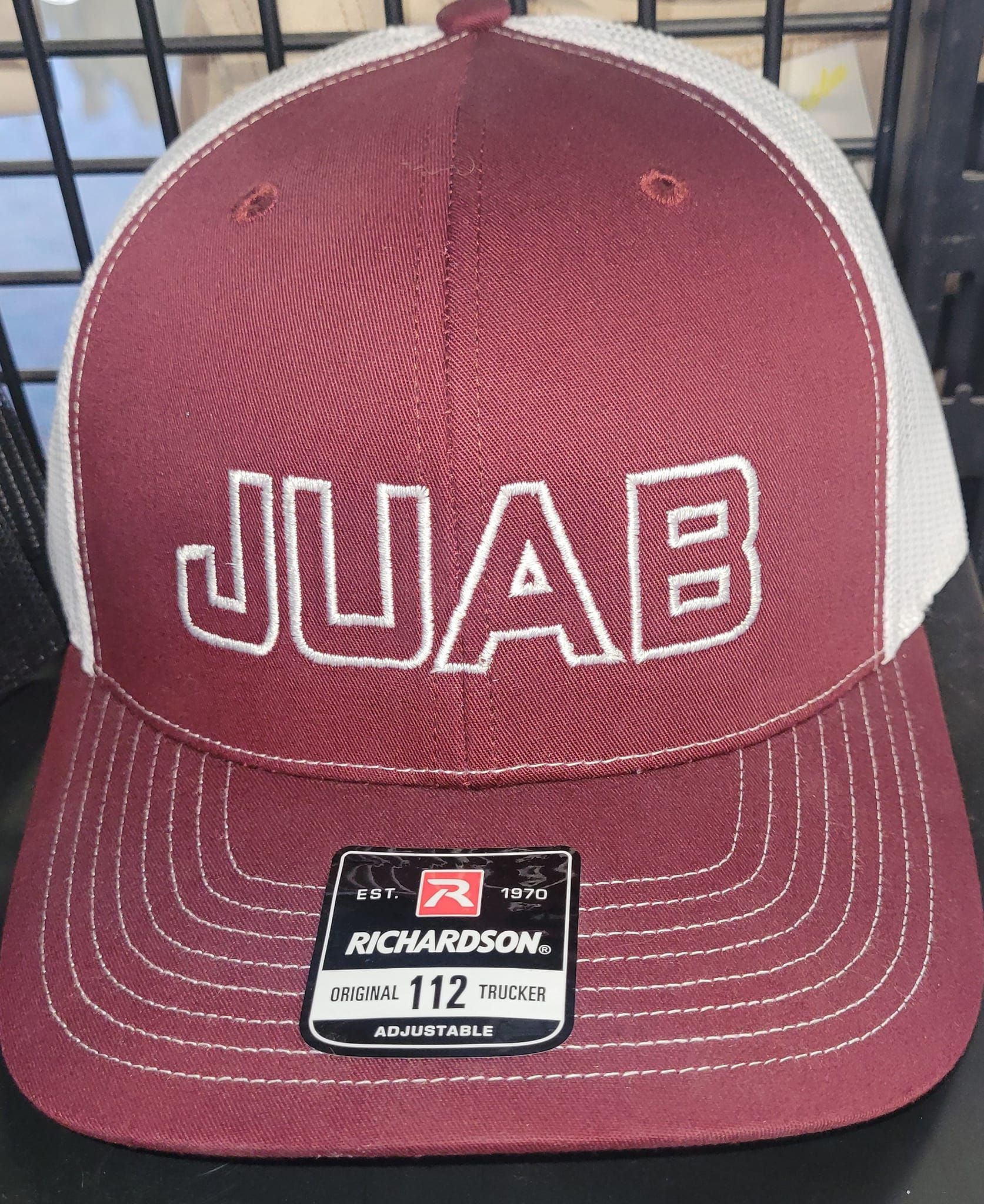 A maroon and white baseball cap with the word juab on it