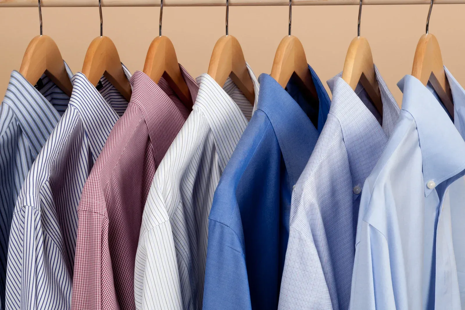A row of shirts hanging on wooden hangers in a closet