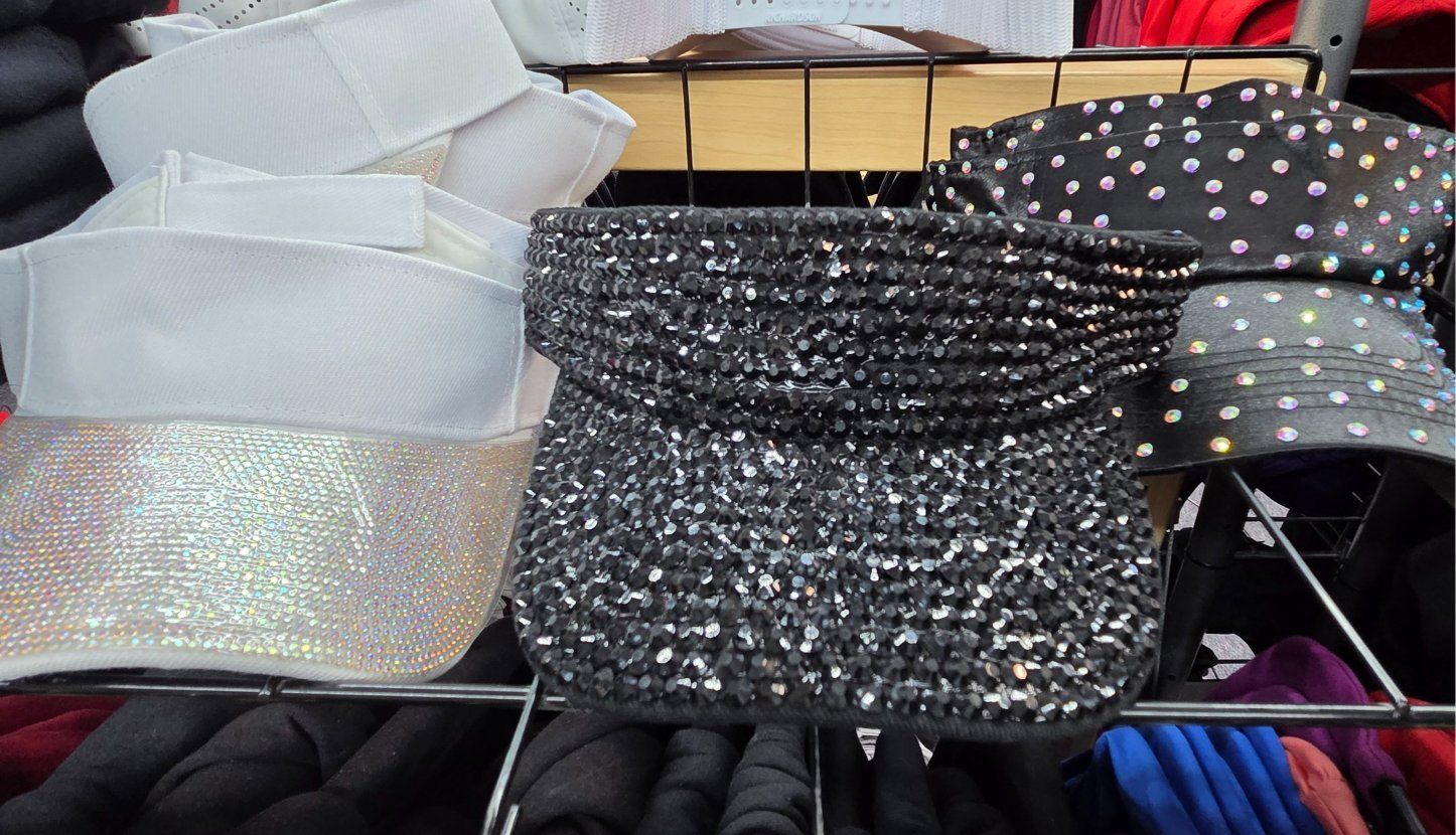 Black and white visors on a store shelf; a sparkly visor is centered.