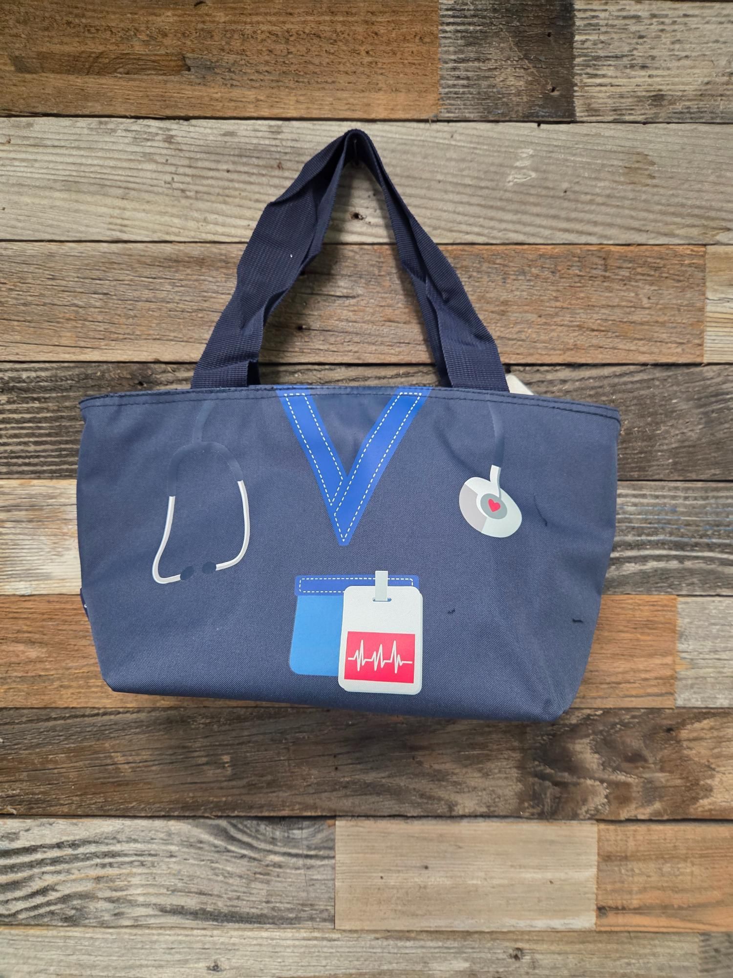 Blue tote bag with nurse uniform design: stethoscope, badge, and blood bag.