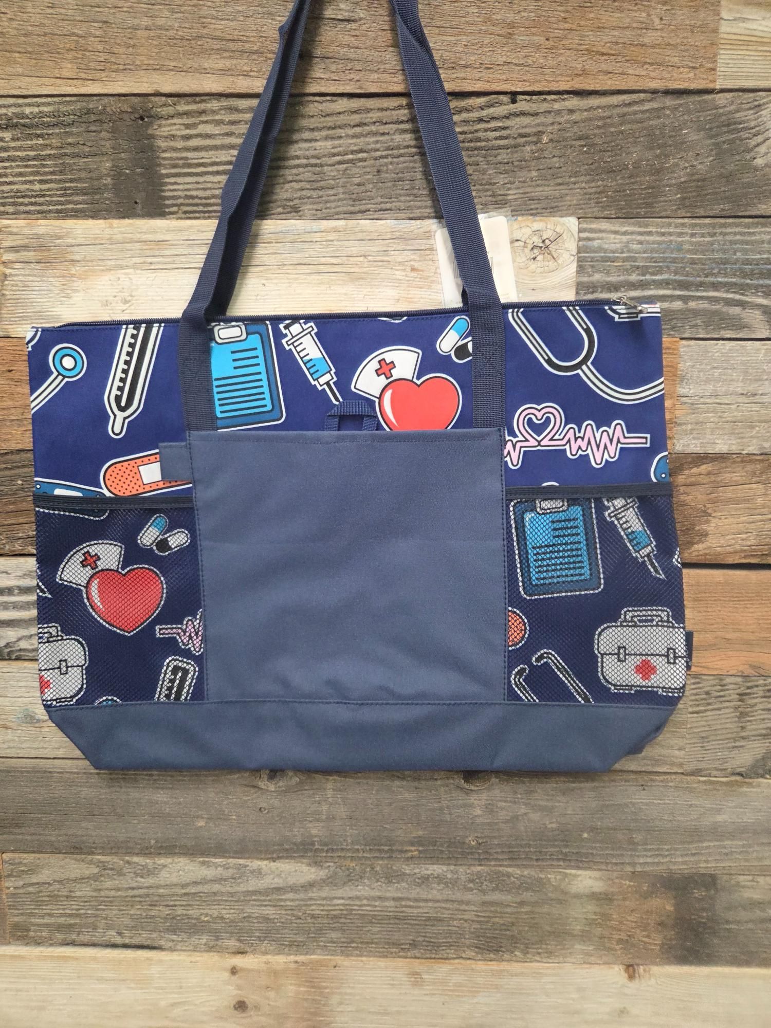 Blue tote bag with medical-themed pattern, pockets, and handles, against a wood-paneled wall.
