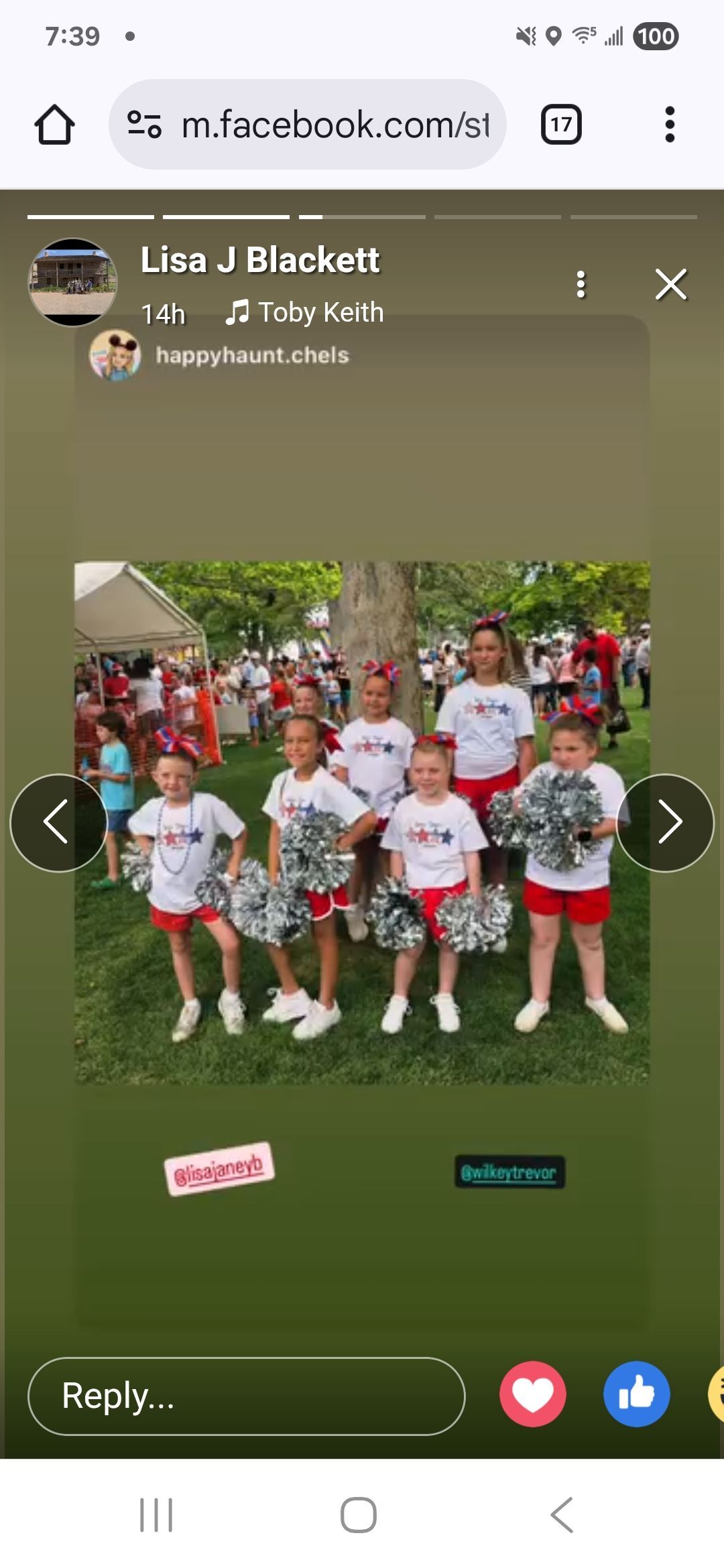 Cheerleaders in white tops and red shorts posing on grass, holding pom-poms.  A crowd in the background.