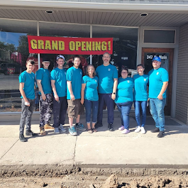 Group of people in teal shirts outside a building with a 