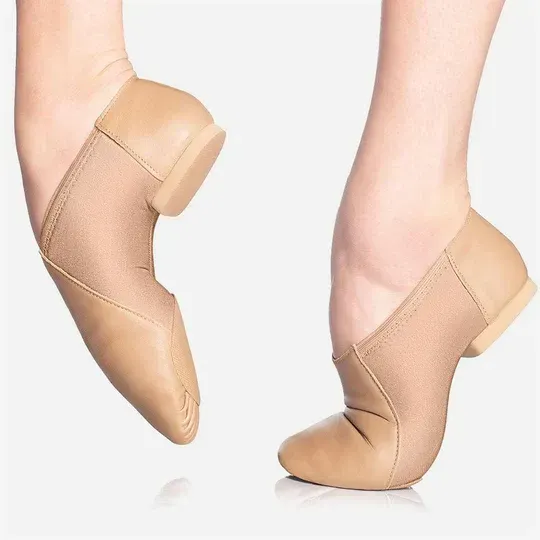 Two beige jazz dance shoes on feet, arched and flexed.