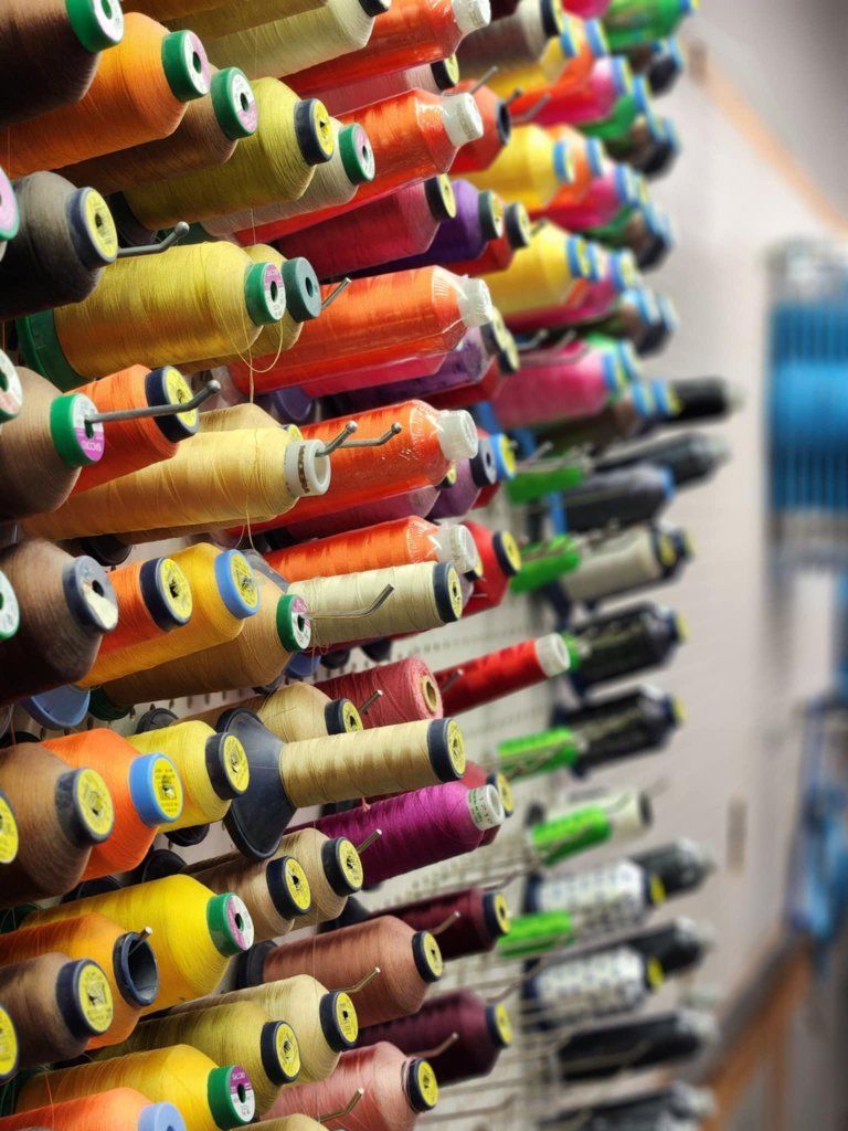 Colorful spools of thread stacked on a shelf in a factory.