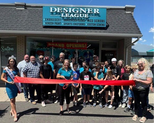 Group cuts a red ribbon in front of Designer League storefront with a 