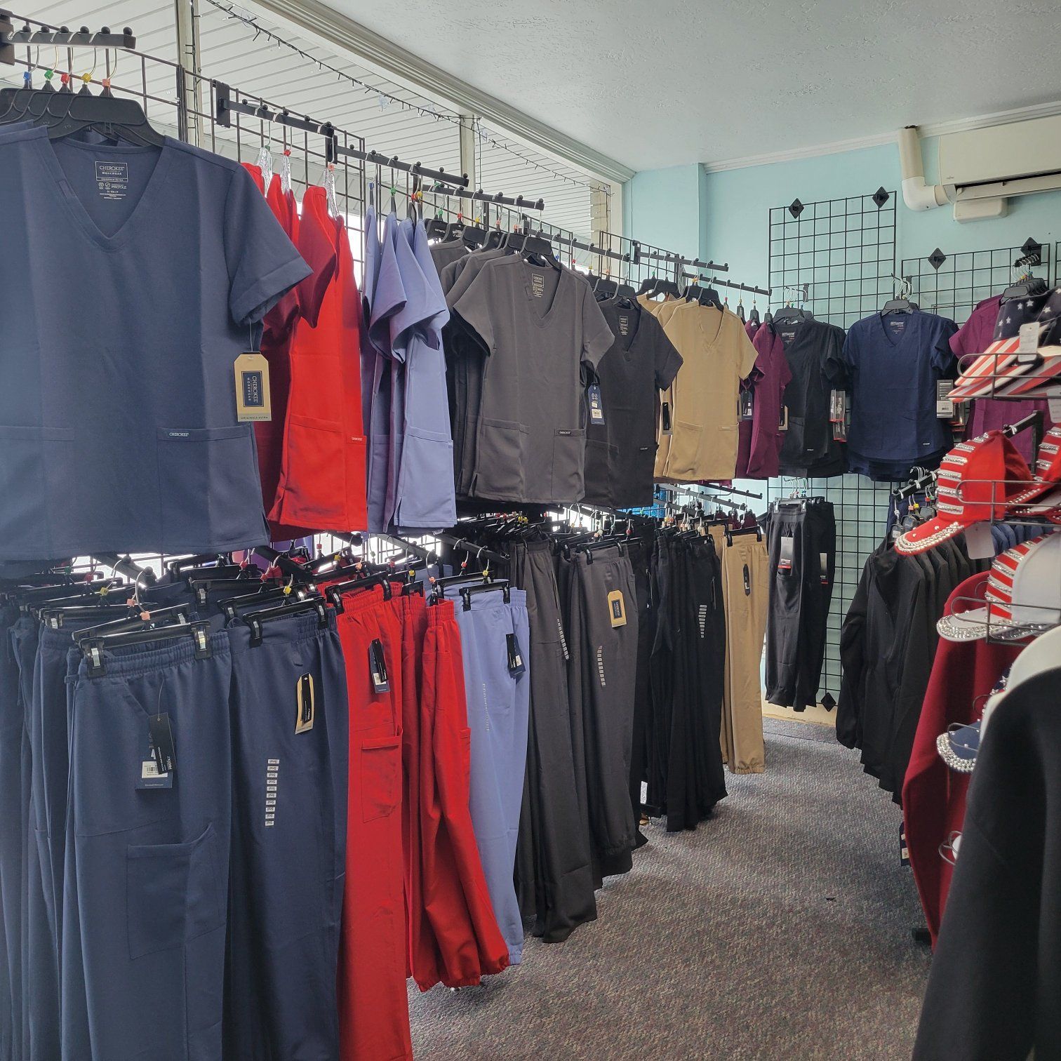 Clothes store interior with various colored scrubs hanging on racks.