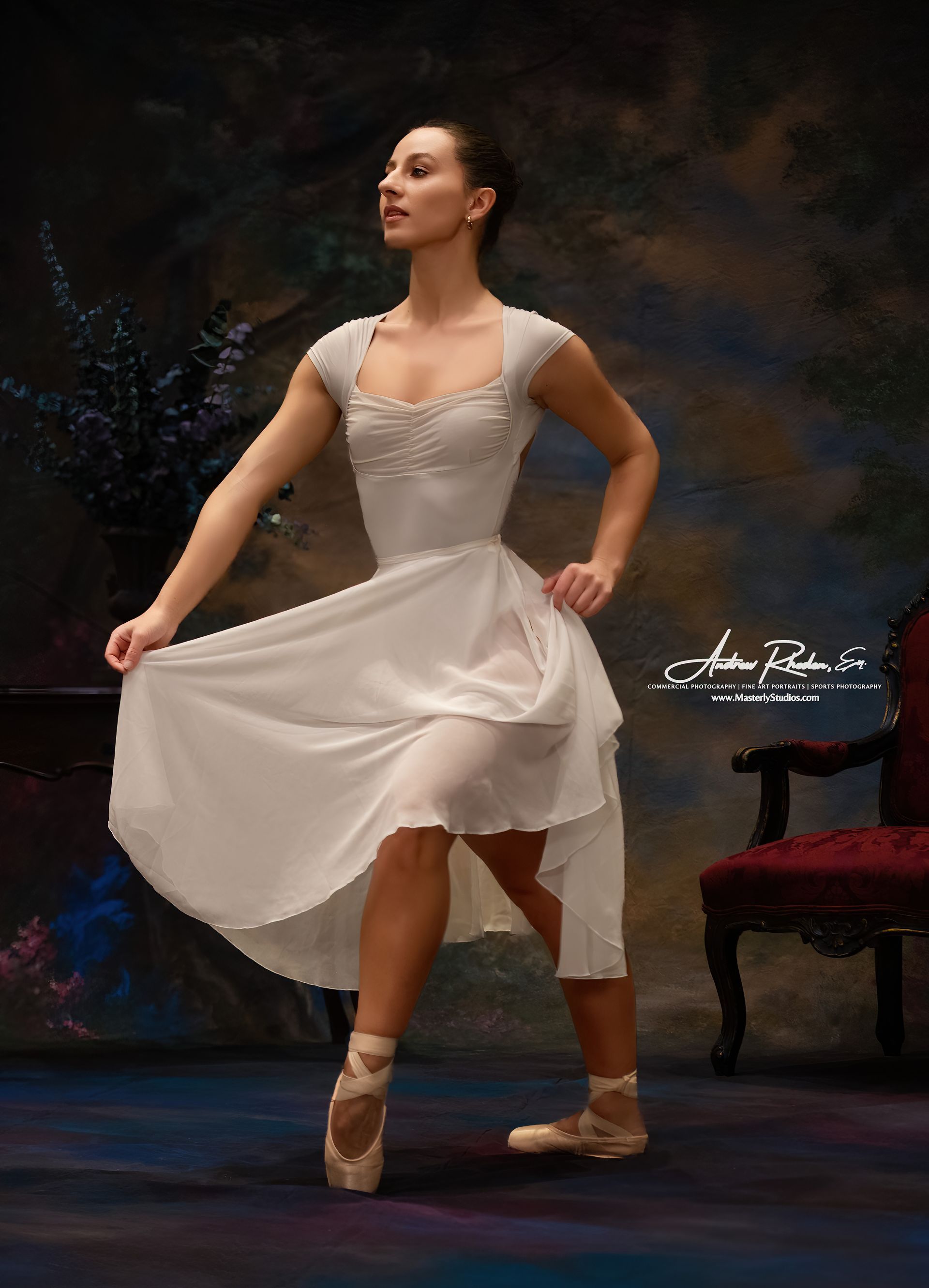 Ballet dancer in white dress, en pointe, arms extended, gazing upward. Stage setting with dark, painted backdrop.