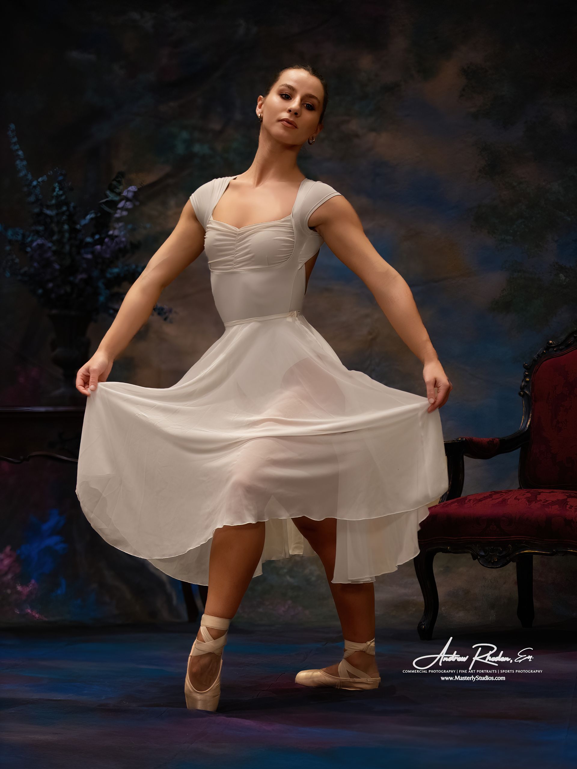 Ballerina in white dress and pointe shoes, holding her skirt up, on a stage with a dark background.