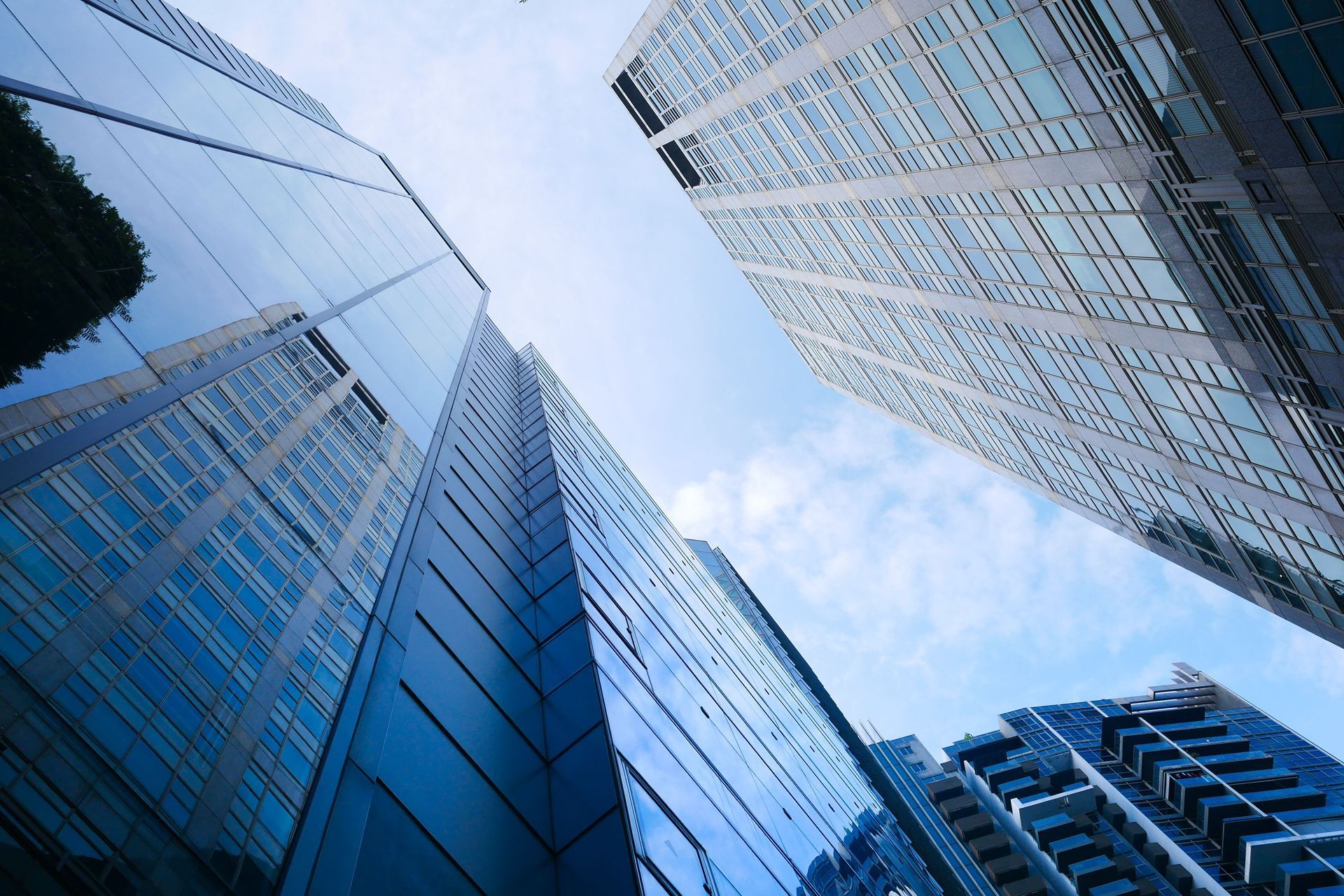 Looking up at glass skyscrapers against a blue sky, creating a dramatic cityscape.