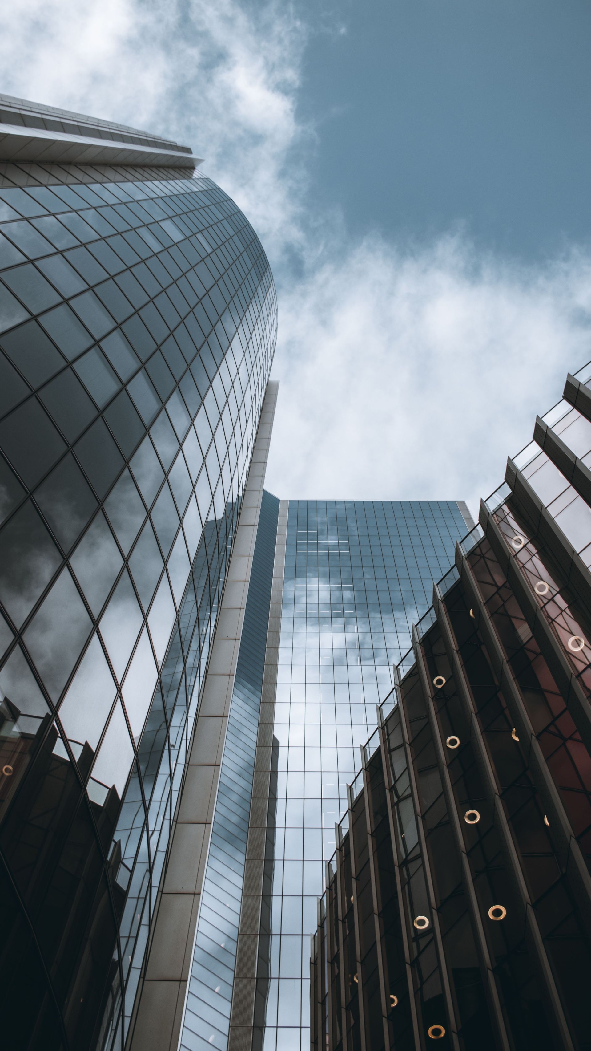 Modern glass skyscrapers viewed from below against a blue sky