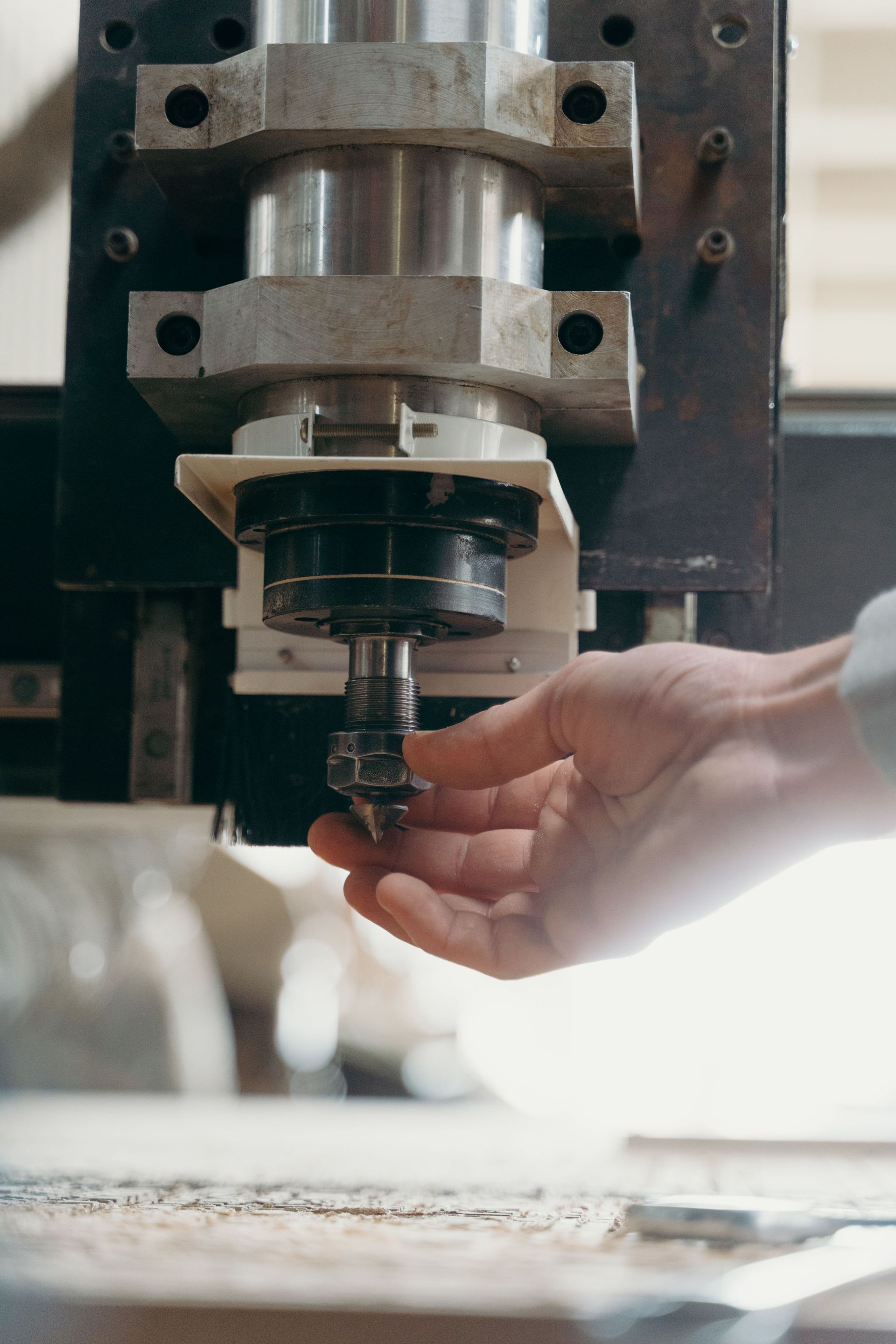 Hand adjusting a drill bit on a milling machine in a workshop