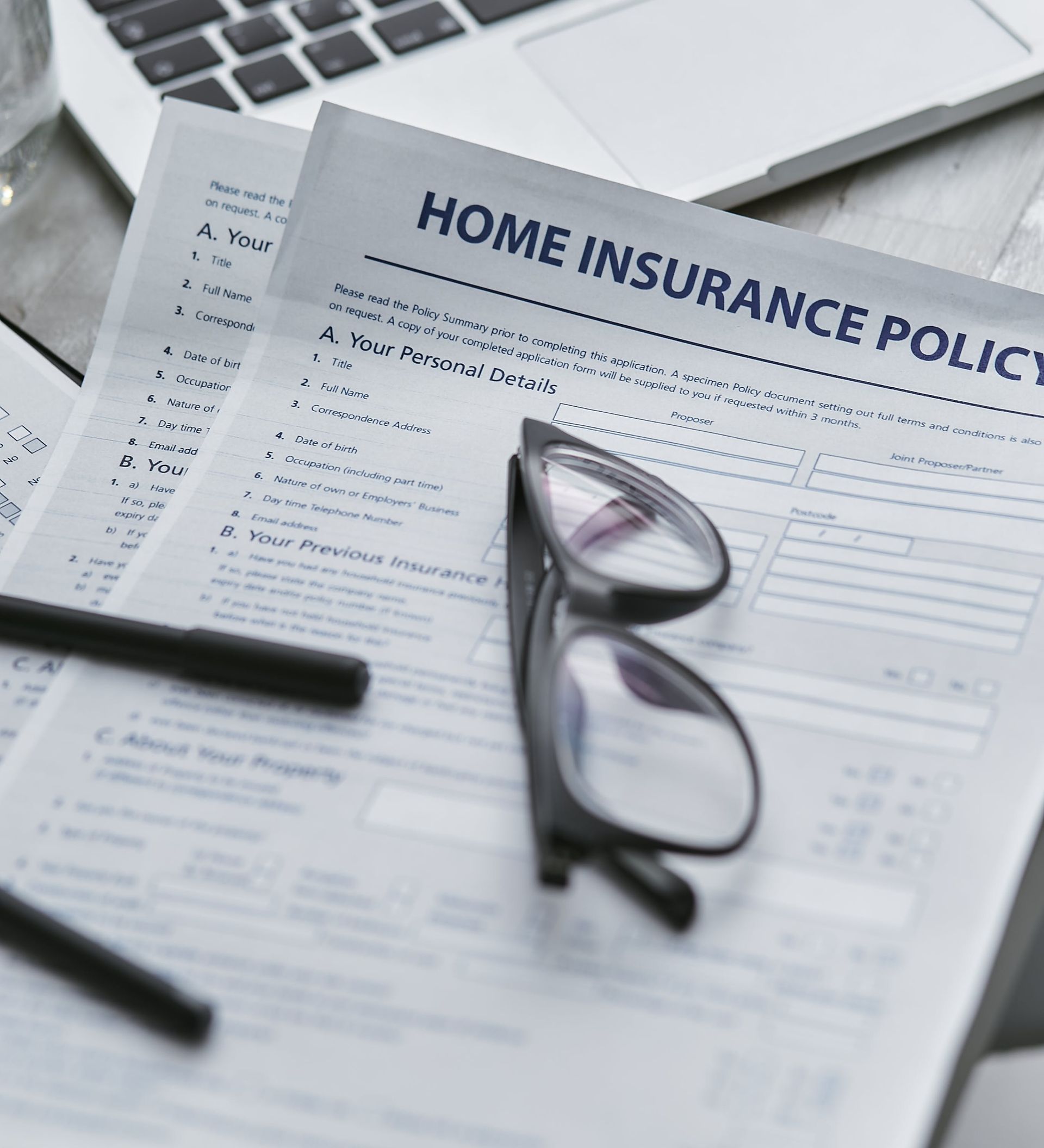 A pair of glasses sitting on top of a home insurance policy
