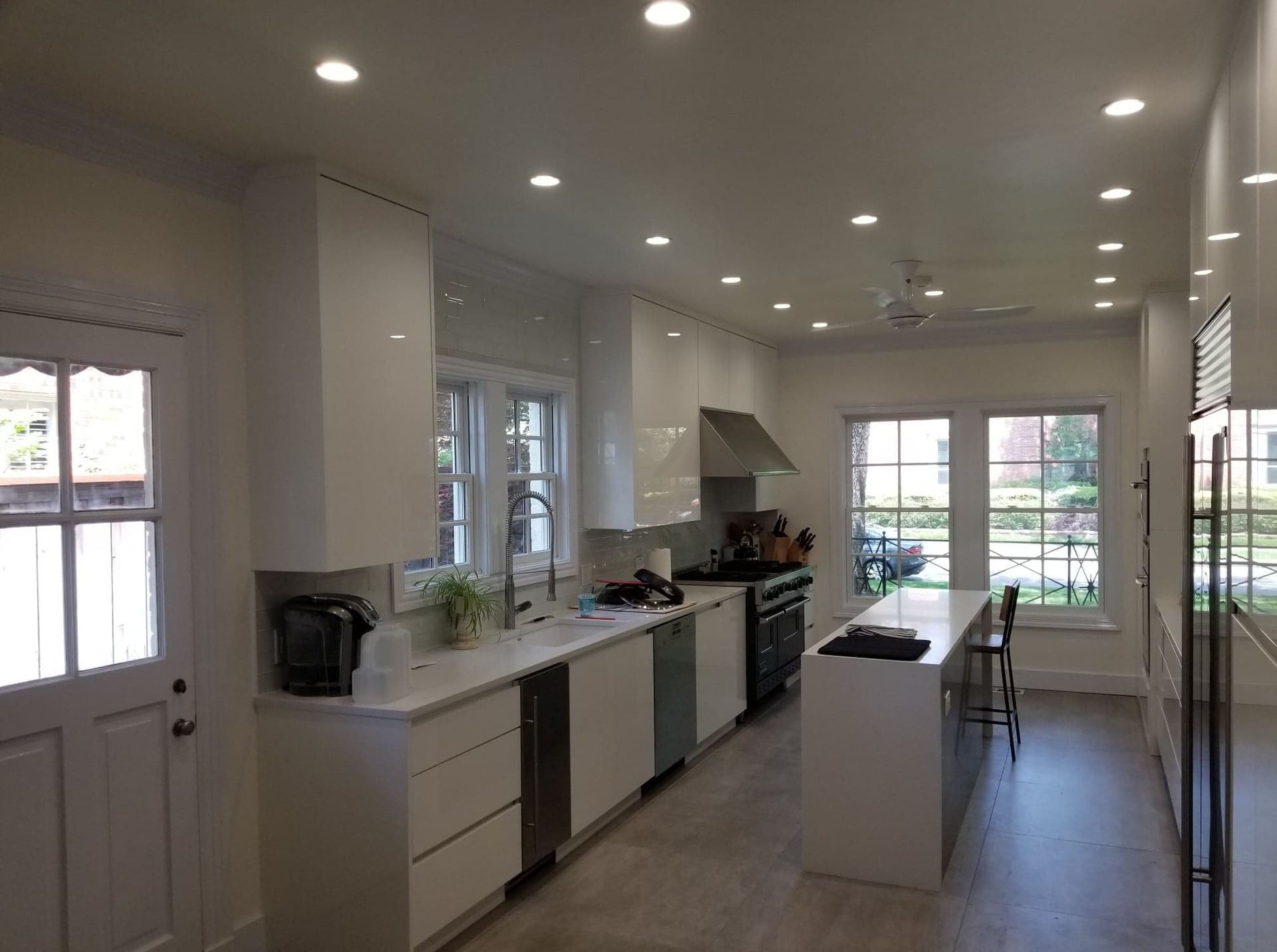 A kitchen with white cabinets , stainless steel appliances , and a large island.