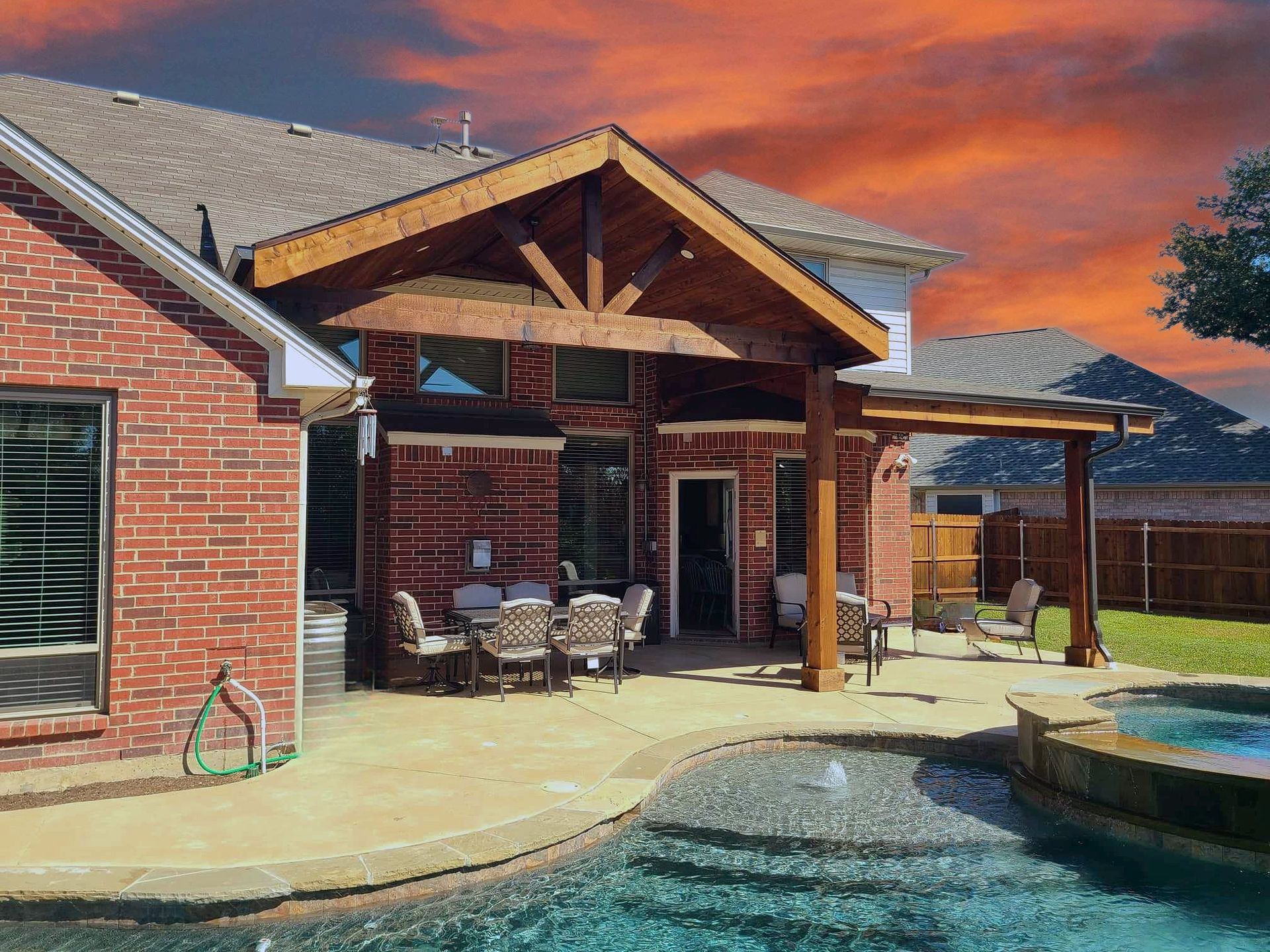 A brick house with a patio and a pool in front of it