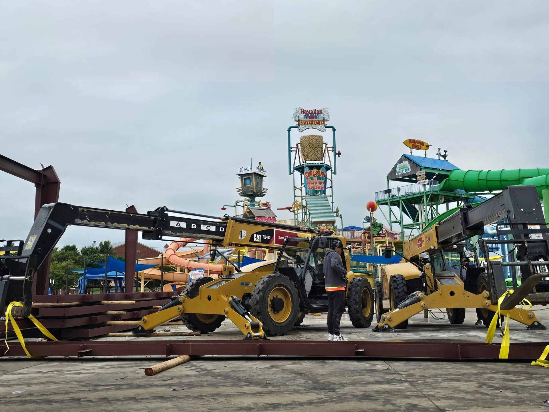 A group of construction vehicles are parked in front of a water park.