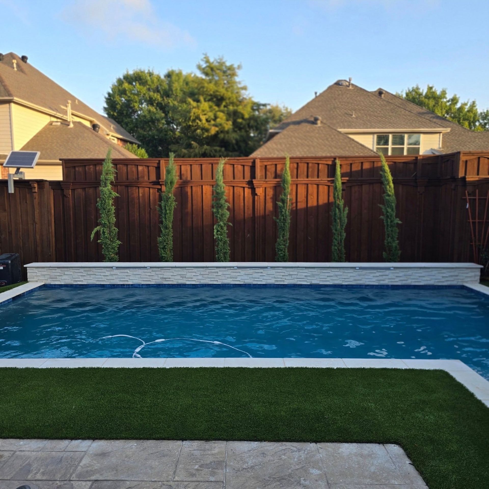 A large swimming pool with a wooden fence surrounding it