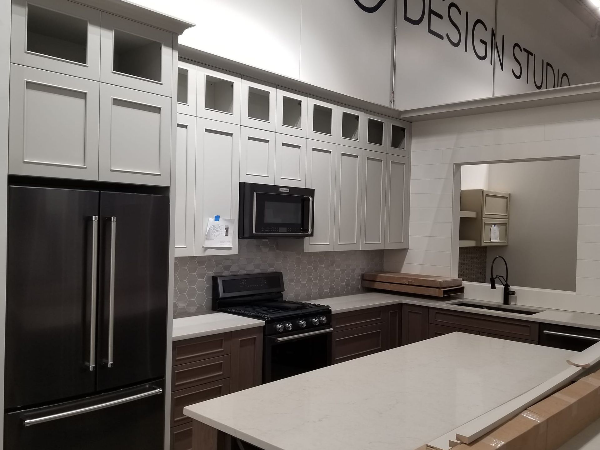 A kitchen with white cabinets , black appliances and a large island.