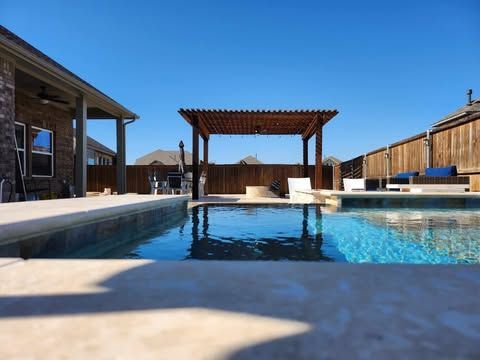 A large swimming pool with a pergola in the backyard of a house.