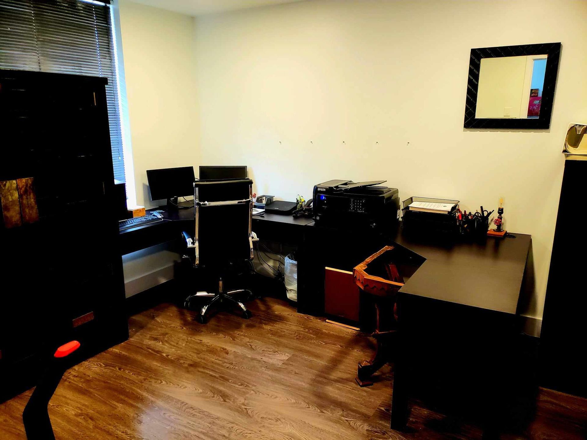 A room with a desk and chairs and a mirror