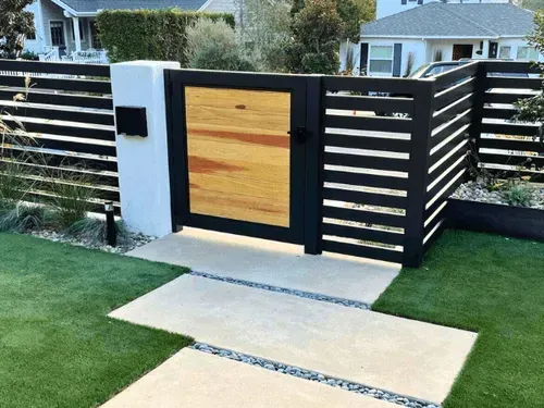 A black and white fence with a wooden gate in front of a house.