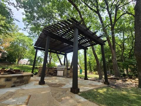 A pergola is sitting in the middle of a lush green forest.