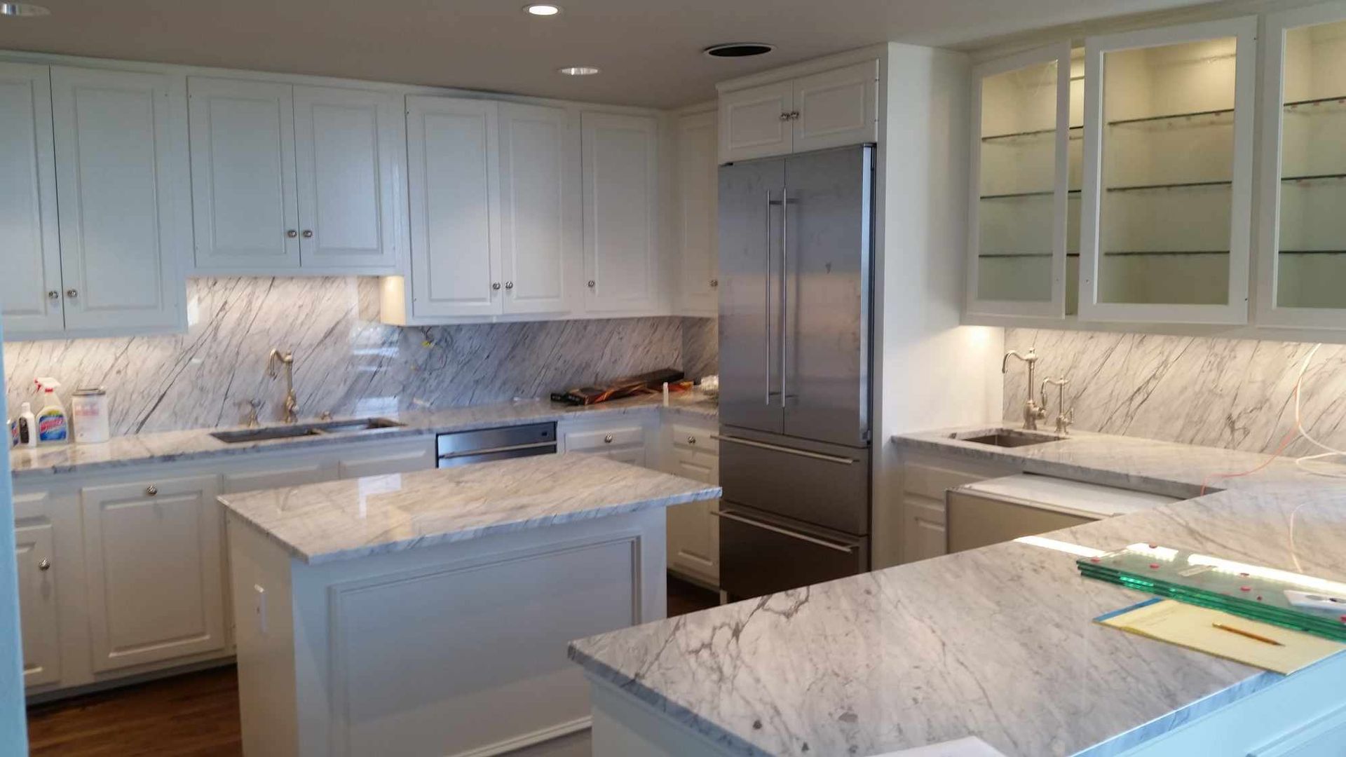 A kitchen with white cabinets , granite counter tops and stainless steel appliances.