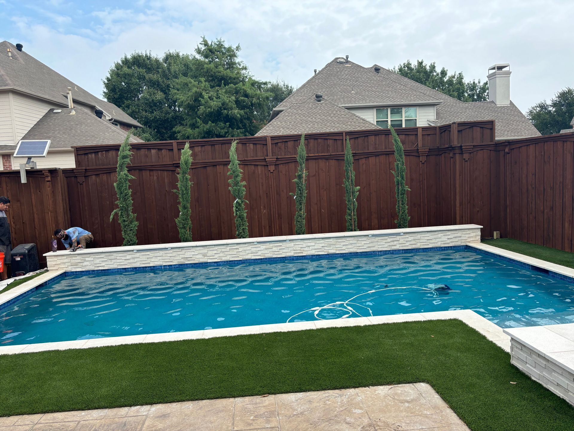 A large swimming pool surrounded by a wooden fence in a backyard.