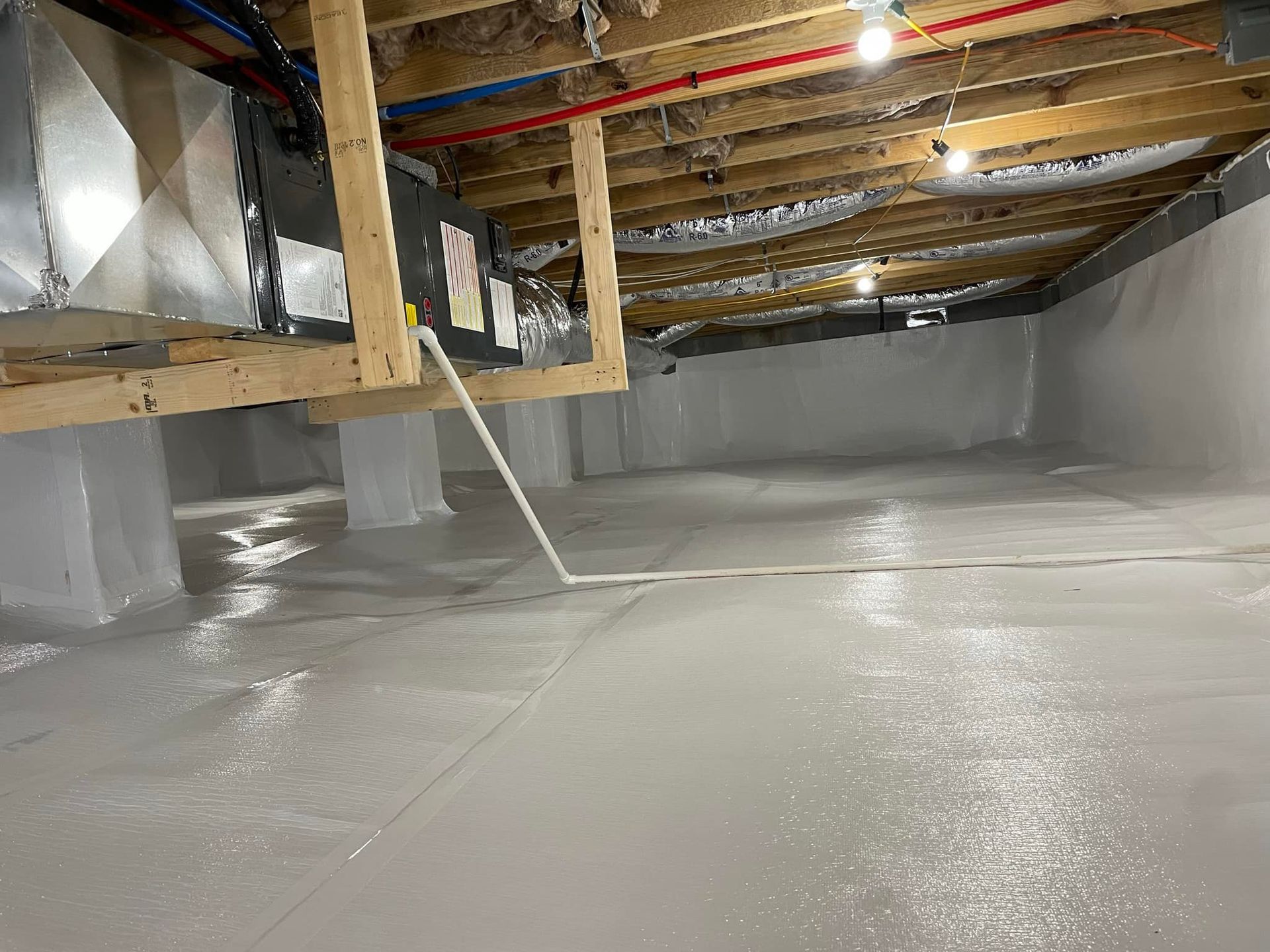 Crawl space with bright white vapor barrier on floor and walls; exposed beams and ductwork above.