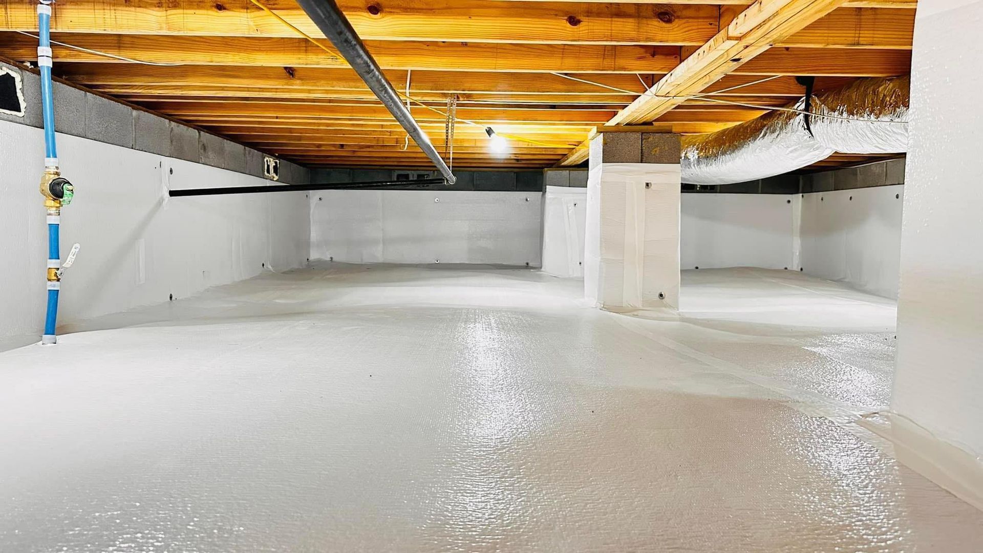 Concrete basement with wood beams and supports; utility pipes visible.