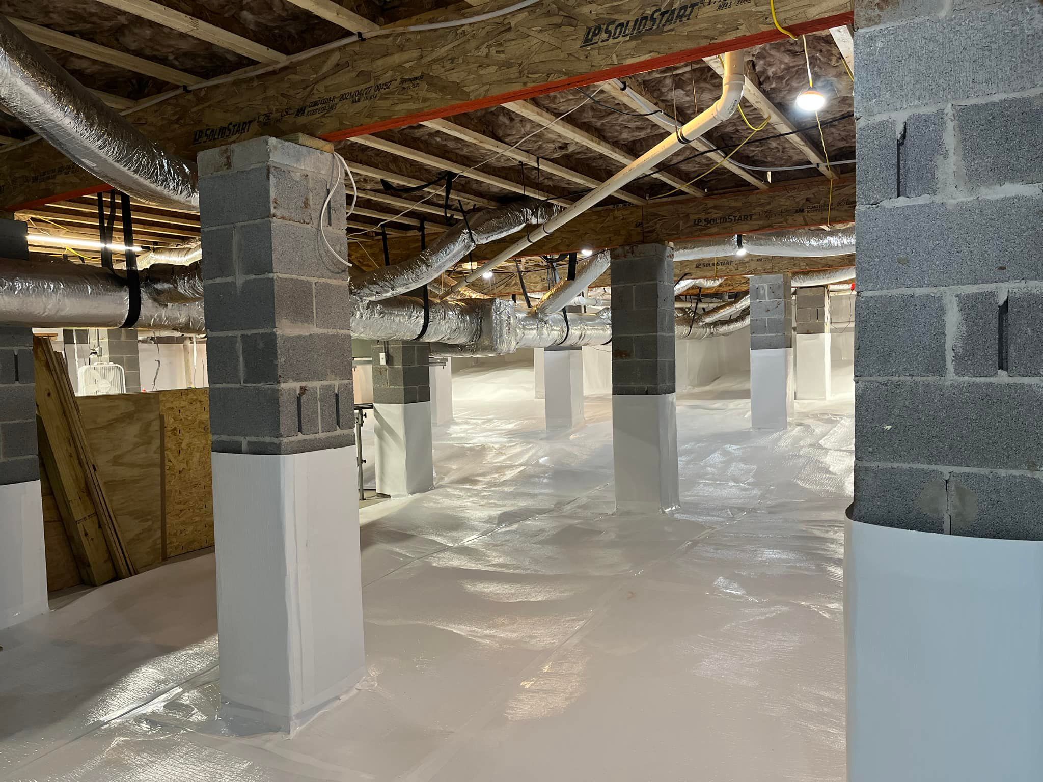 A crawl space with block columns, insulation, and ductwork.