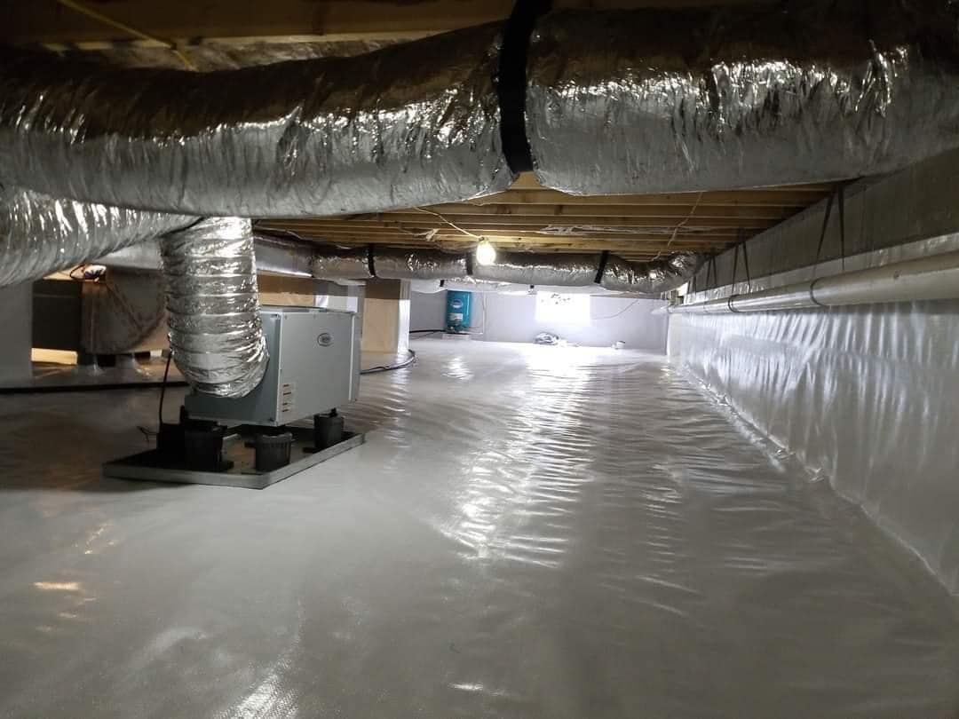 Crawlspace with white vapor barrier flooring and silver ductwork overhead.