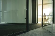 Glass-walled office with dark trim. A sunny interior space is visible.