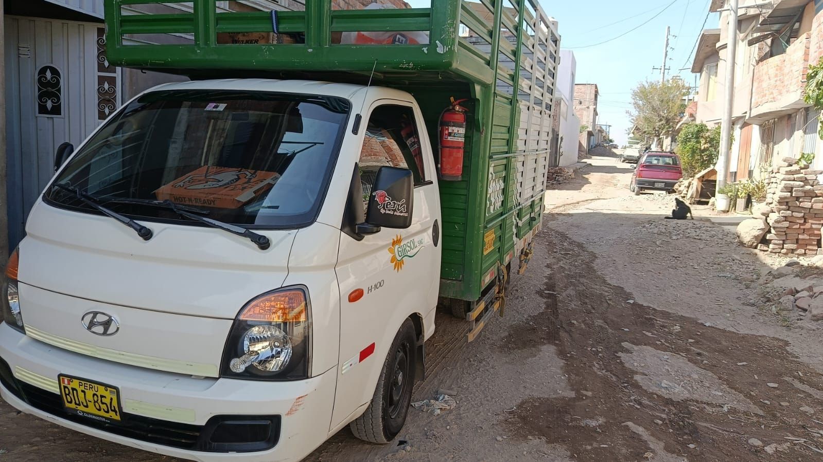 Camioneta Hyundai blanca con bodega verde en un camino de tierra. Extintor rojo instalado.