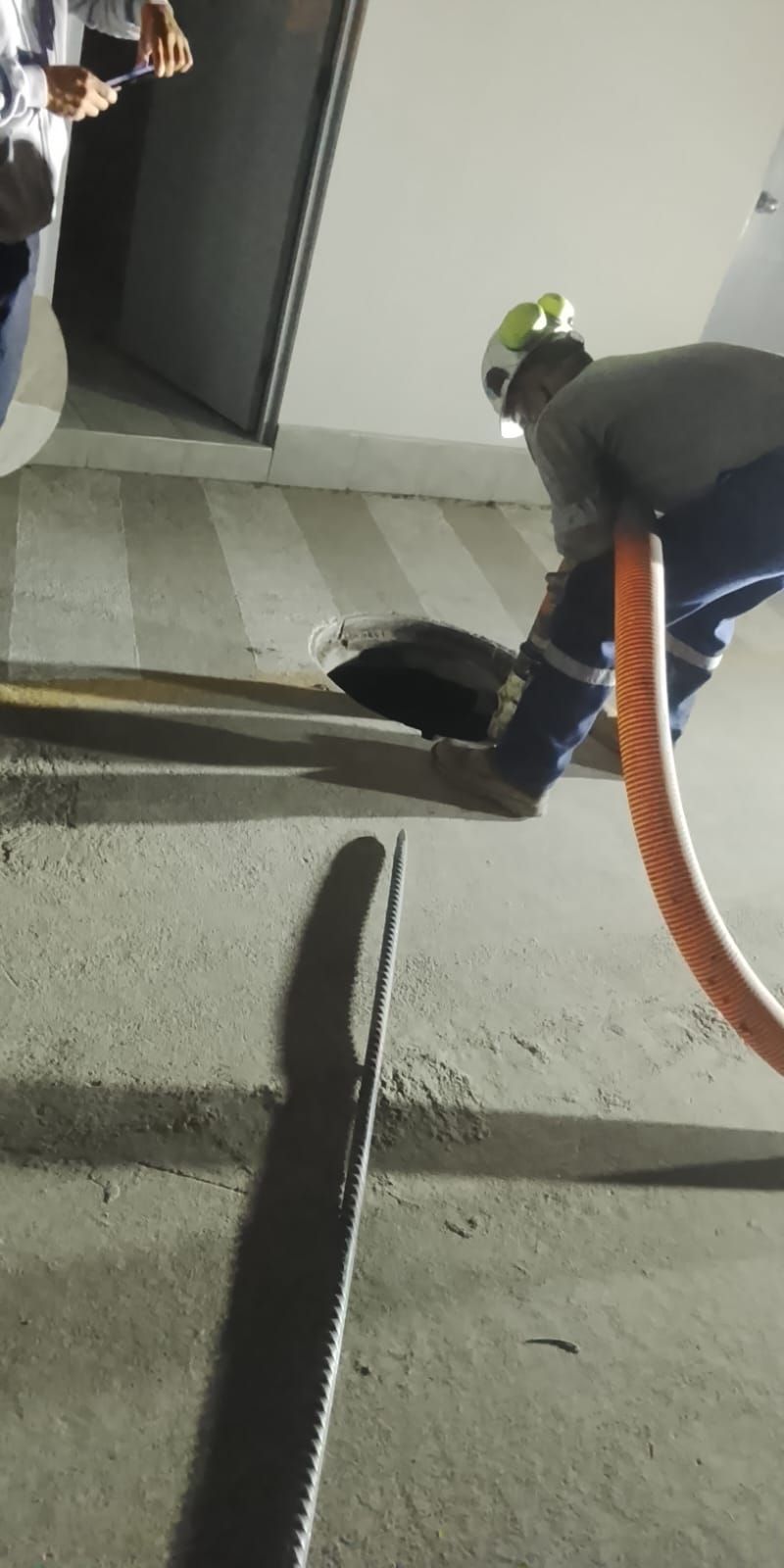 Persona con equipo de seguridad trabajando con una manguera cerca de un agujero en una pared.