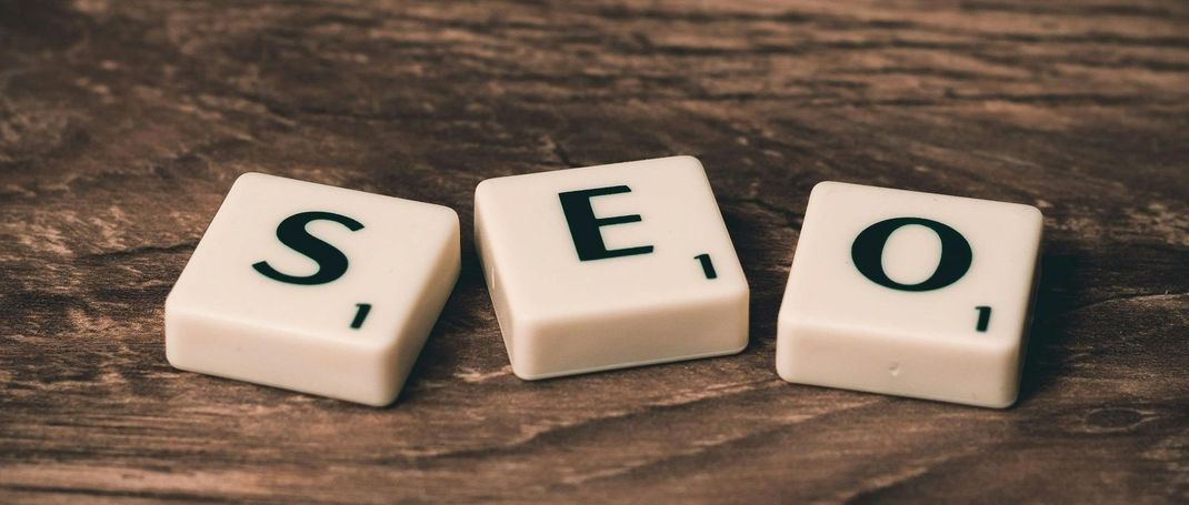 The word seo is written on scrabble tiles on a wooden table.