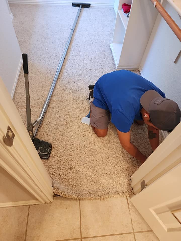 Person kneeling in a closet installing carpet with tools.