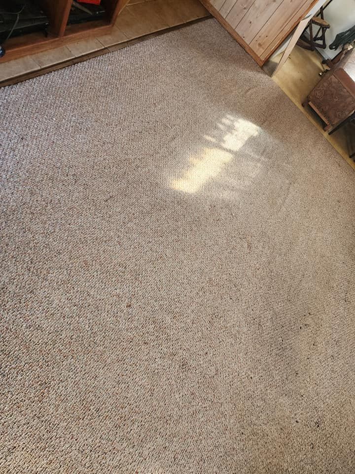 Beige carpeted floor with light shining on it, near wooden furniture.