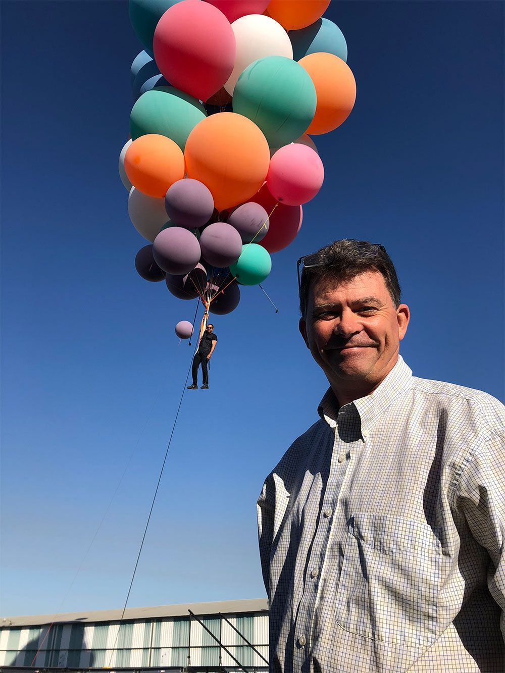 A man is standing in front of a bunch of balloons