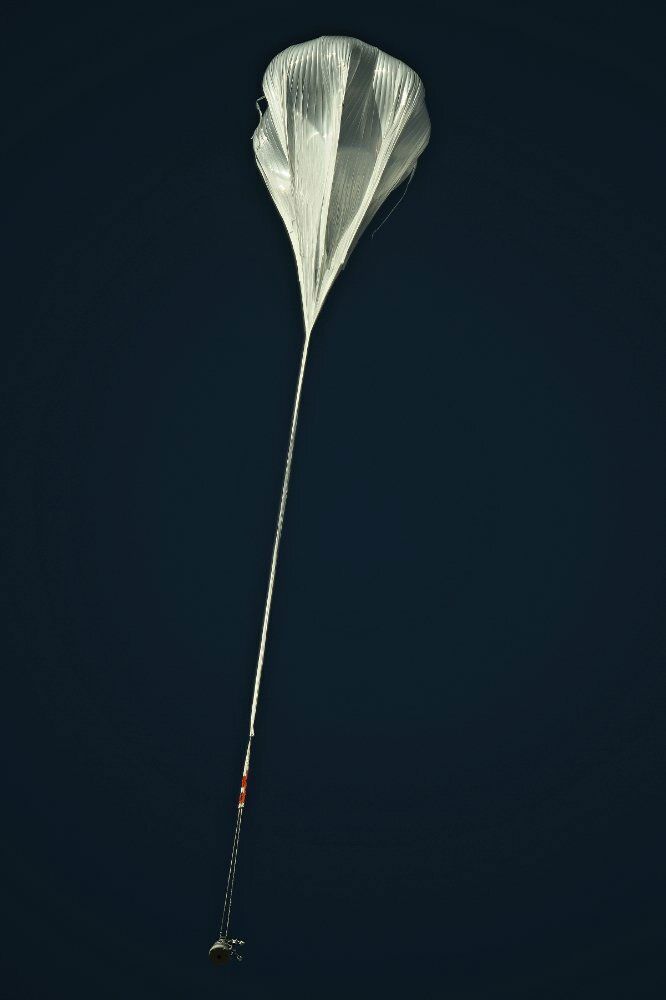 A white parachute is flying through a dark blue sky.