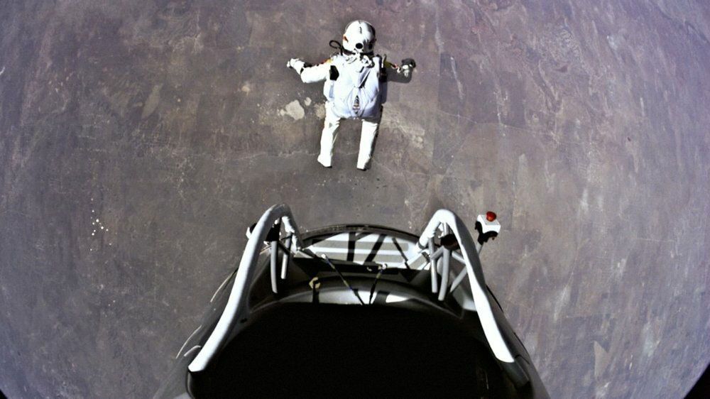 A man in a space suit is standing next to a car