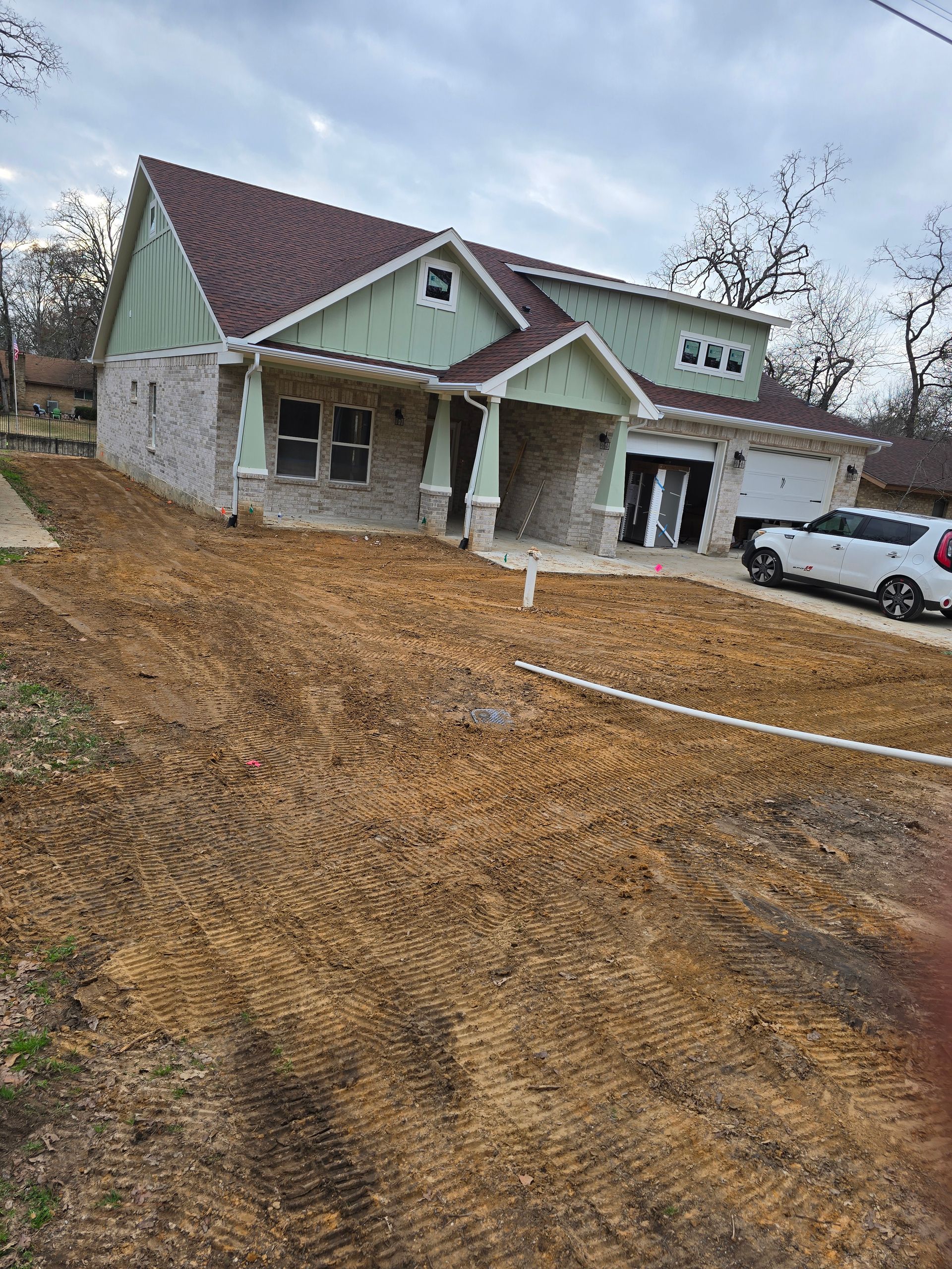 People working on lawn care by a waterfront, operating machinery, on a sunny day.