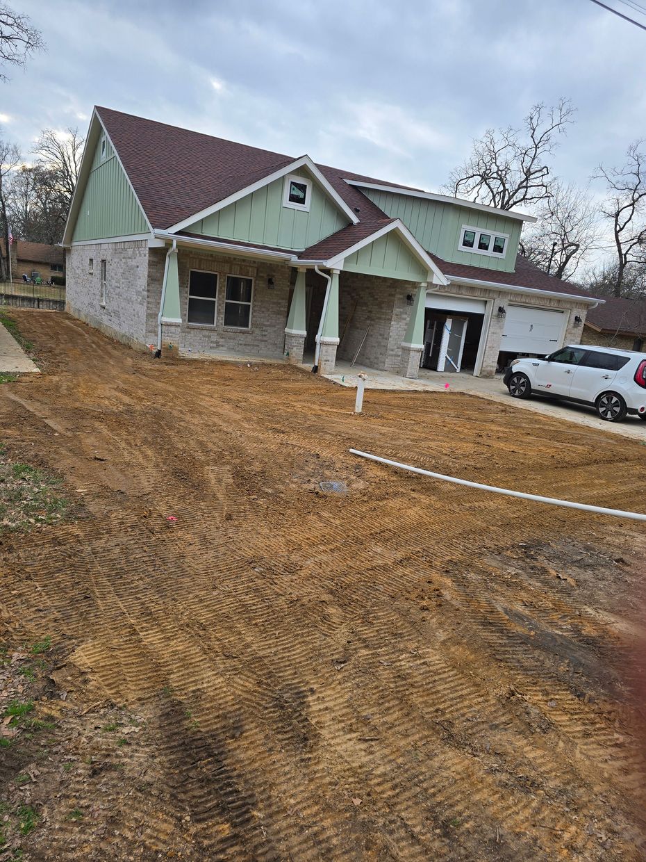 Men working on landscaping near a pond; one drives a small tractor, an eagle statue is in the foreground.