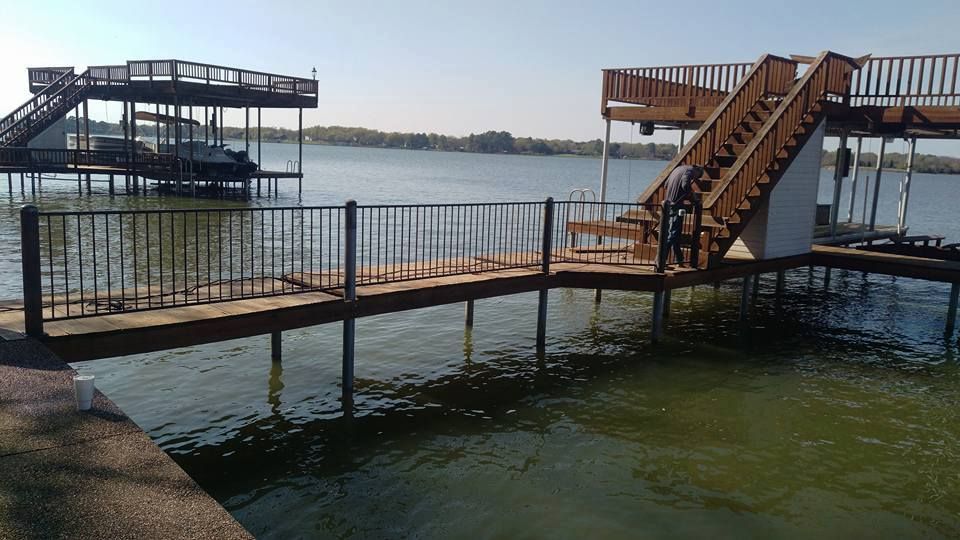 Wooden docks with stairs leading to a boat house on a lake. Person walking down stairs.