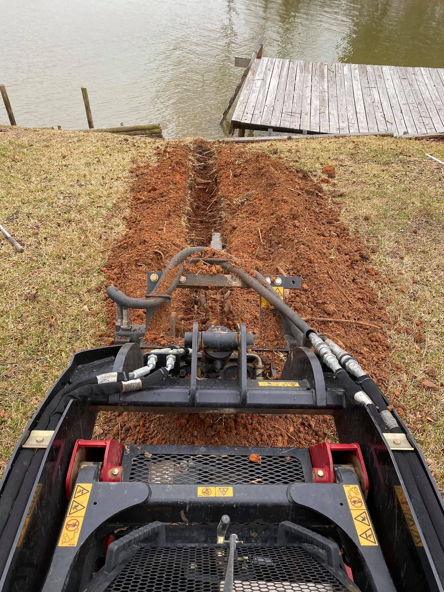 Bobcat clearing a wood chip path to a dock on a lake.